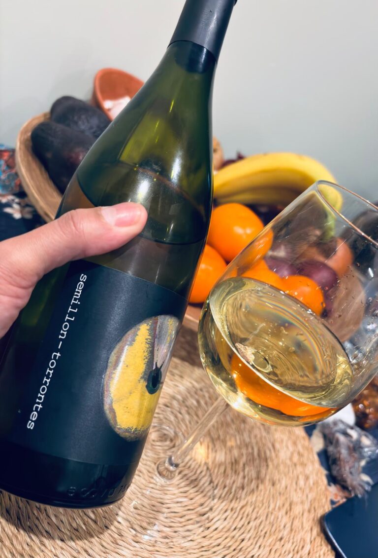 hand holding a botle of wine with a fruit background